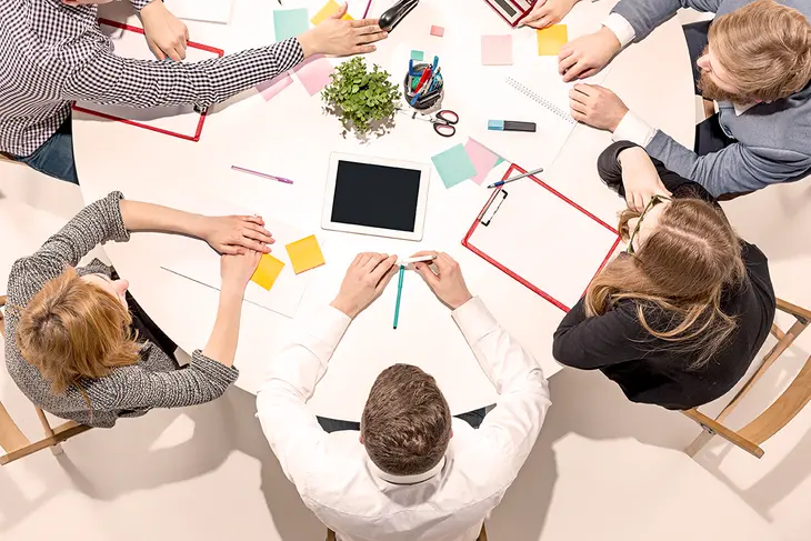 A group of professionals exchanging business cards at a networking event, symbolizing the connections and opportunities for collaboration fostered through networking for innovators